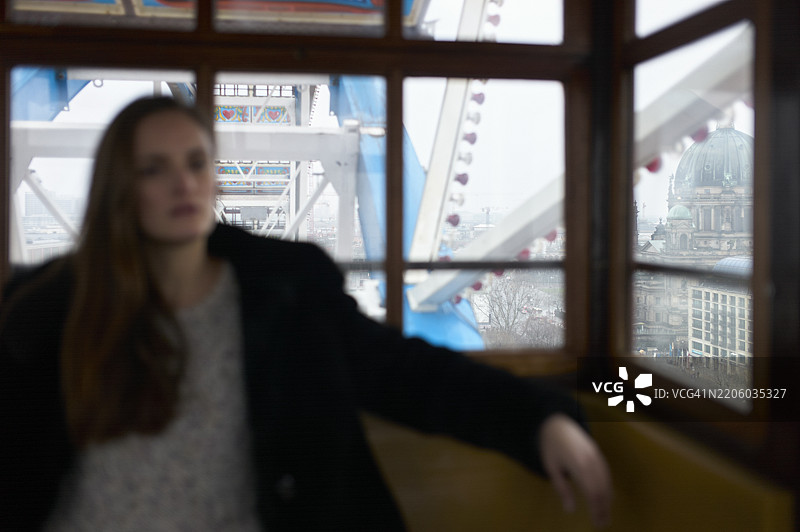 模糊的女性在摩天轮的舱内，窗外可见城市风景。德国柏林图片素材