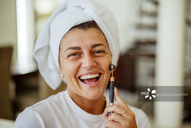 自我护理时刻：女性在家中使用玉石滚轮为自己拍照图片素材