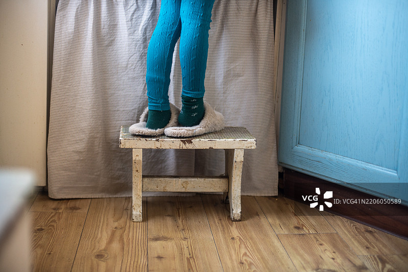 小女孩的腿搭在厨房水槽旁的凳子上图片素材