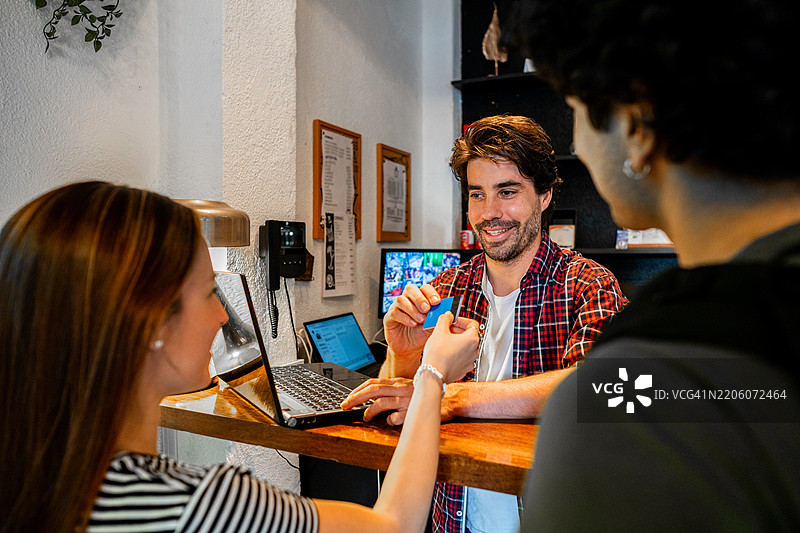 中年男性接待员在旅馆前台接收顾客的信用卡图片素材