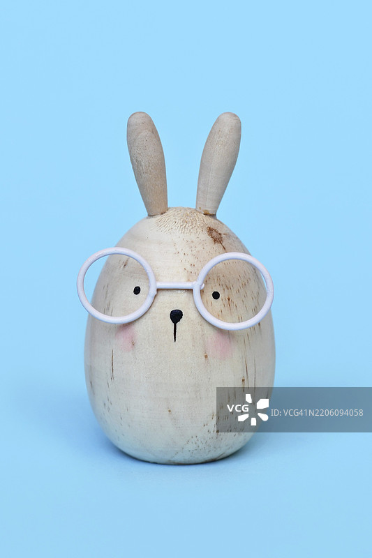 可爱搞笑的蛋形复活节兔子戴着眼镜，背景为蓝色图片素材