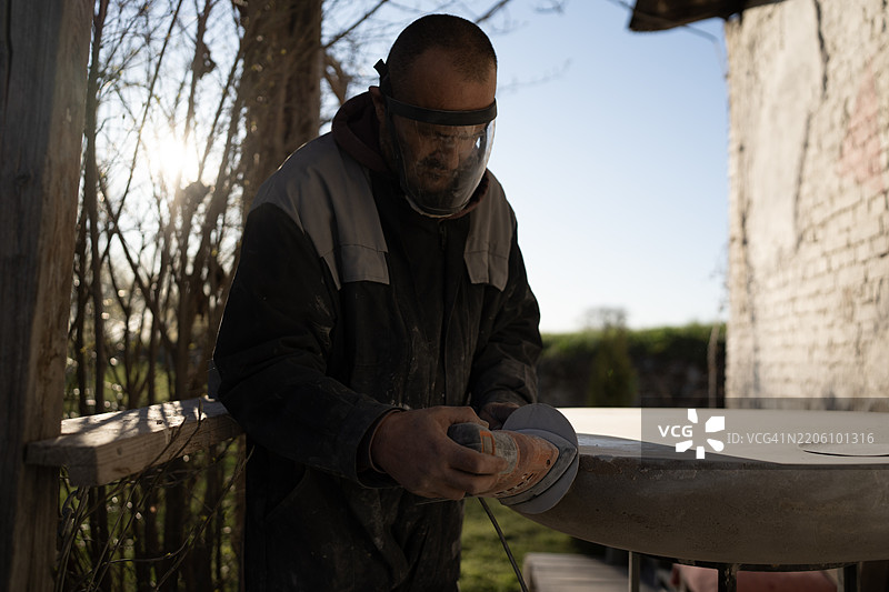 工人在自然光下户外打磨石材表面图片素材