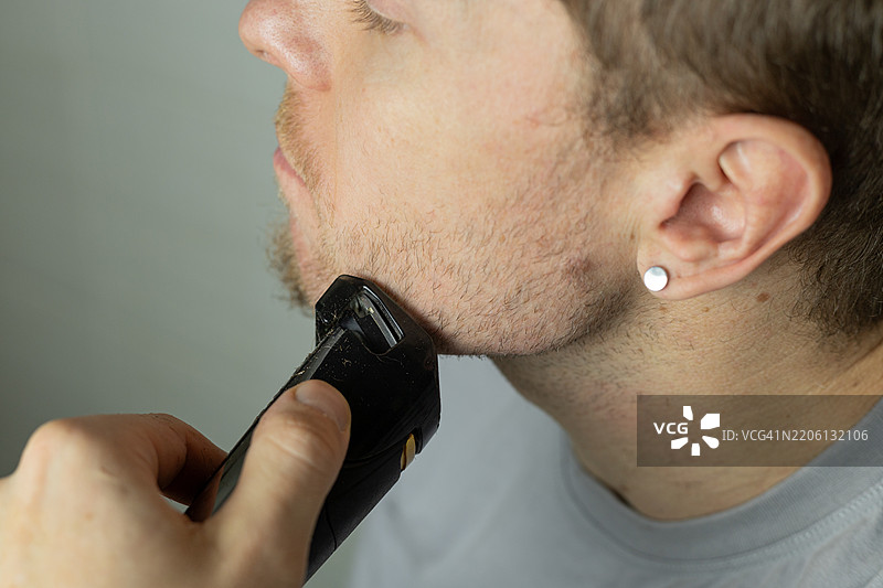 男子用修剪器修剪胡须 特写 电动剃须刀修剪胡须 家庭胡须护理图片素材