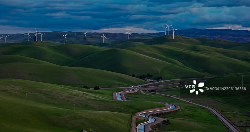 宽幅照片展示了通往阿尔塔蒙特山口风车的水渠支流弯曲的景象图片素材