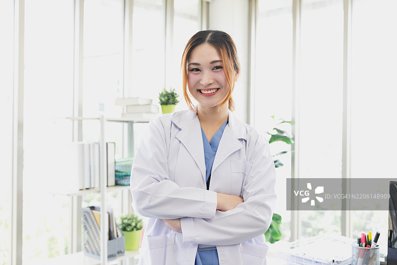 医疗专业人士在明亮的办公室环境中自信地站立，背景有绿色植物和用品。图片素材