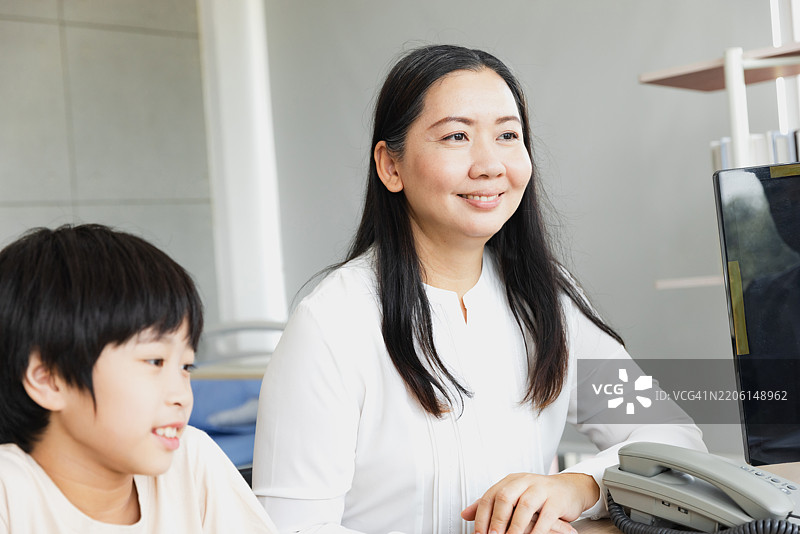 母亲和儿子在明亮现代的工作空间中一起探索科技，正值白天。图片素材