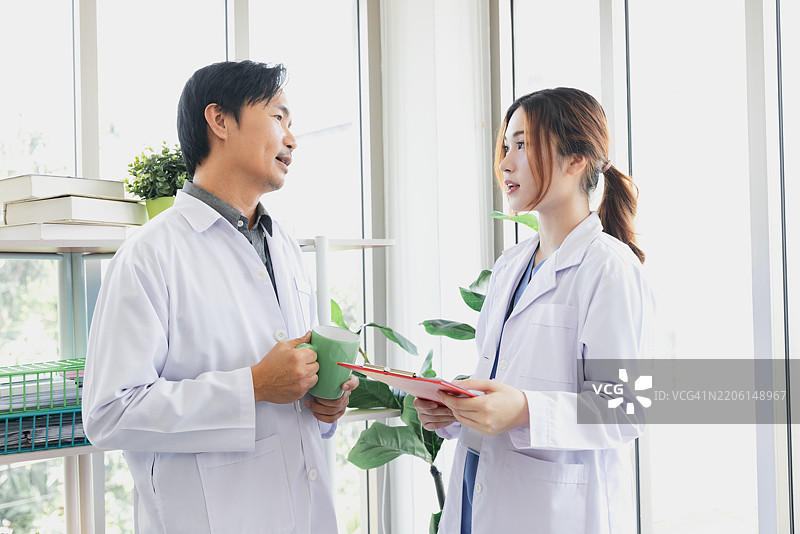 医疗专业人士在明亮的诊所中讨论患者护理，白天时分。图片素材