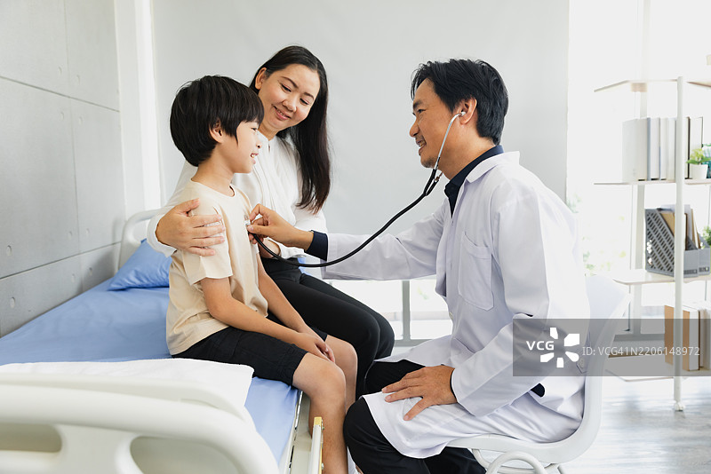 医生在现代诊所白天检查孩子的心跳，母亲在旁观看。图片素材