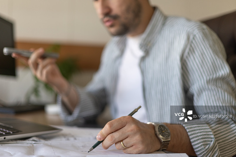 建筑师在办公室使用语音识别软件并绘制项目蓝图图片素材