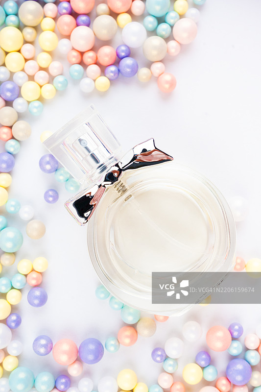 白色香水瓶和多彩的粉彩珠子在白色背景上。图片素材