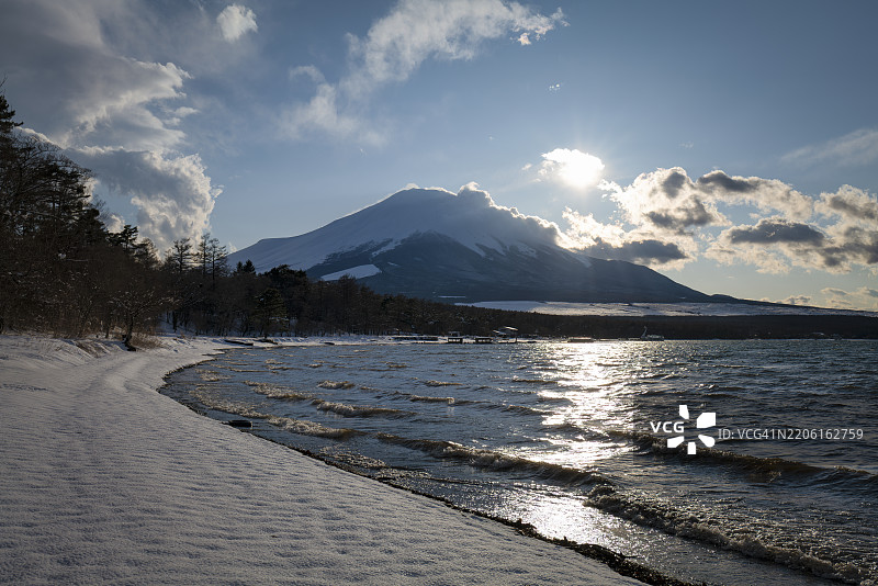 冬季富士山与阳光映照在山中湖和雪-covered海岸上图片素材