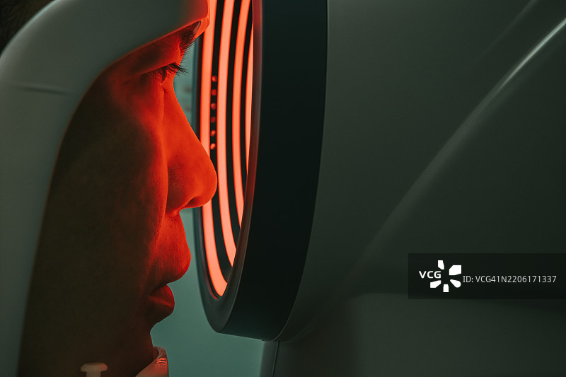 亚洲男性在眼科诊所进行眼睛检查，进行视网膜扫描测试视力。图片素材