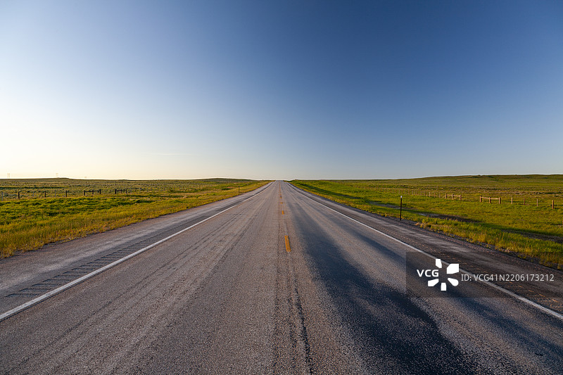 怀俄明州 – 一条空旷的道路延伸穿过广袤的草原景观图片素材