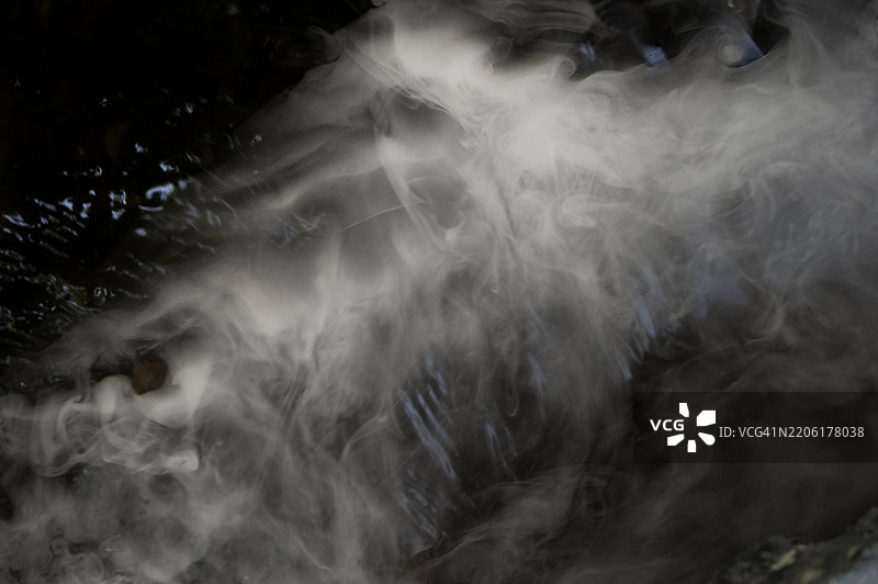 一幅模糊的溪流图像，上面漂浮着白色的雾气。场景宁静而平和，雾气营造出一种平静与安宁的感觉。图片素材