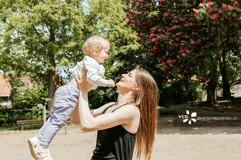 妈妈在公园里和孩子玩耍，和他一起旋转。图片素材