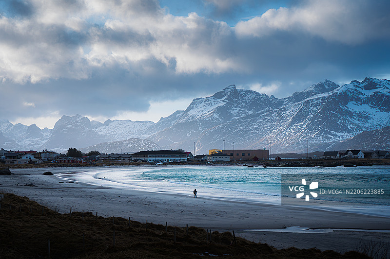 弗拉克斯塔德海滩，背景是山脉，天空的倒影映在海浪上，摄影师和他的三脚架，挪威洛福滕群岛。图片素材