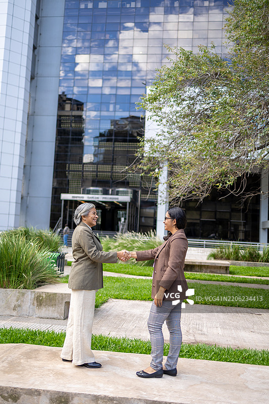 两位职业女性在现代商业区户外握手图片素材