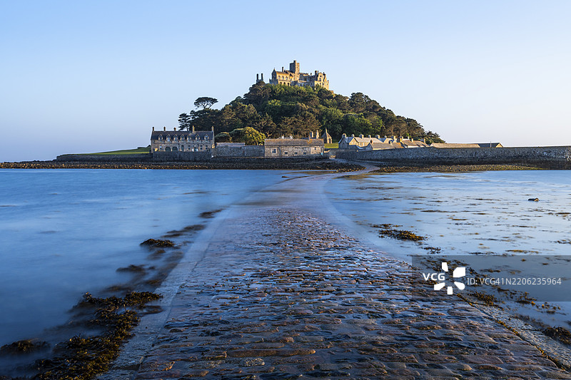 圣迈克尔山的景观,前方是被潮水稍微冲刷过的堤坝或小路。傍晚,金色时光。圣迈克尔山,马拉齐翁,康沃尔,英格兰,英国图片素材