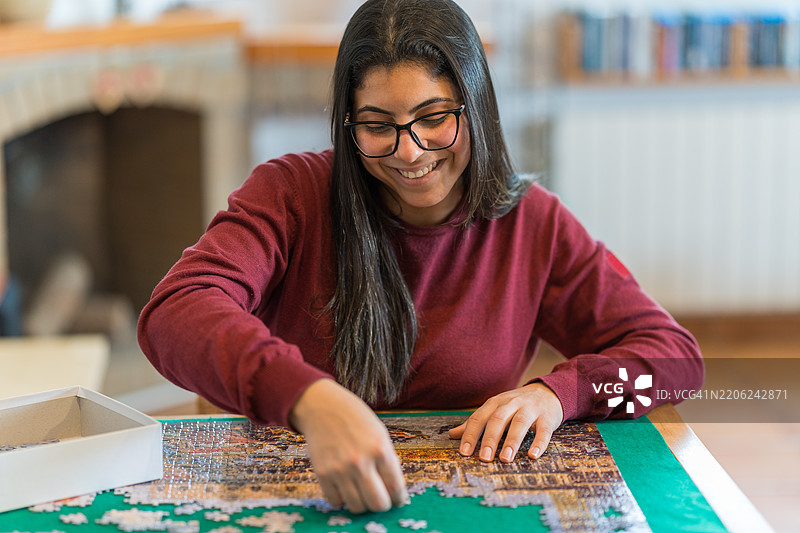 年轻女性在家专注于拼图游戏图片素材