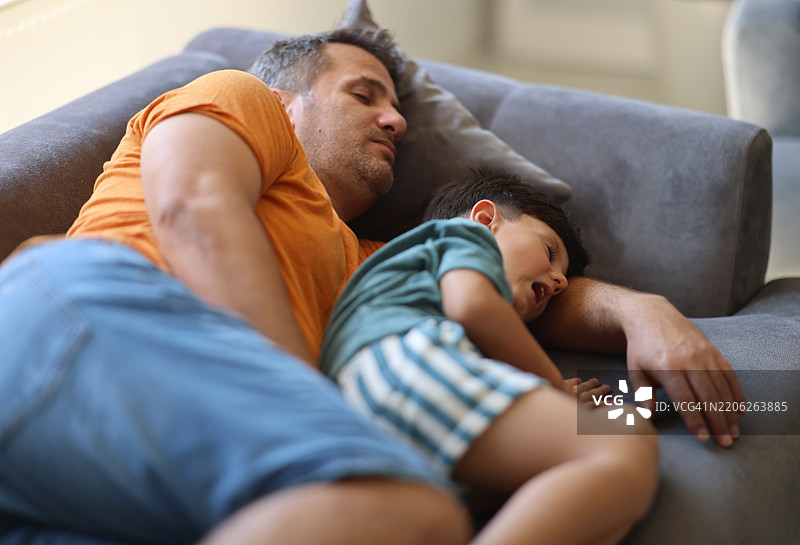 父亲和儿子在客厅的沙发上一起睡觉图片素材