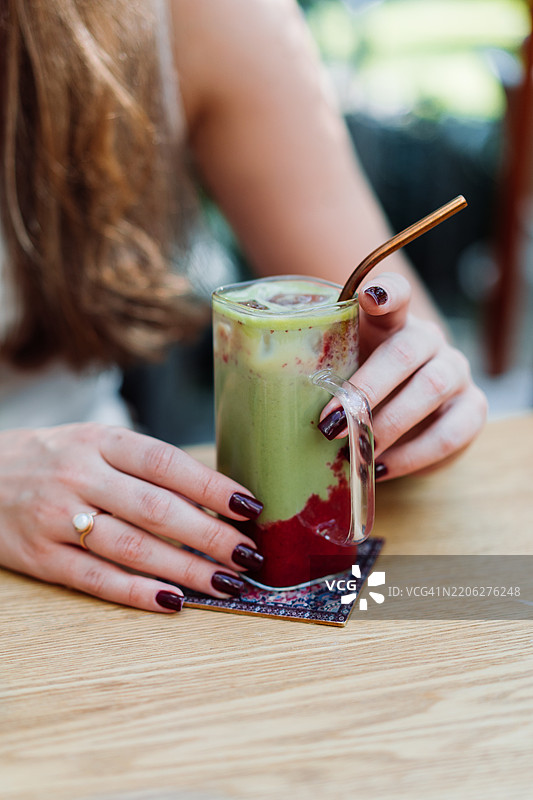 年轻女性在户外自然光下享用健康的果昔饮品图片素材