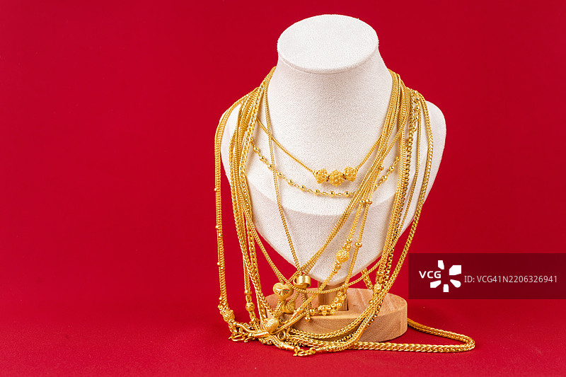配饰和金饰项链展示架，上面放着金项链，背景是红色天鹅绒布料。图片素材