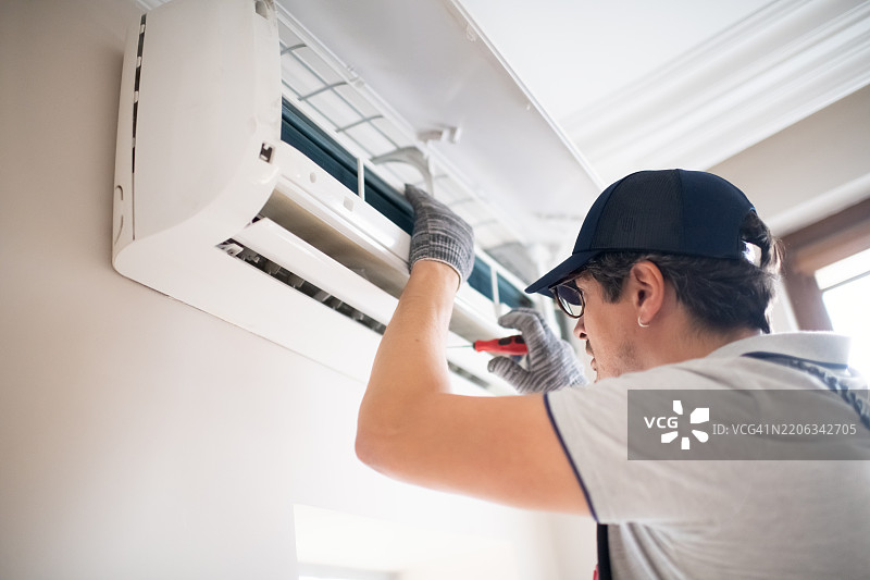 技术人员在家中用螺丝刀修理空调图片素材