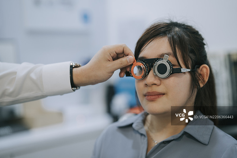 亚洲医生在诊所为一位有残疾的年轻女性患者进行视力测试，使用光学视力测试图表。图片素材