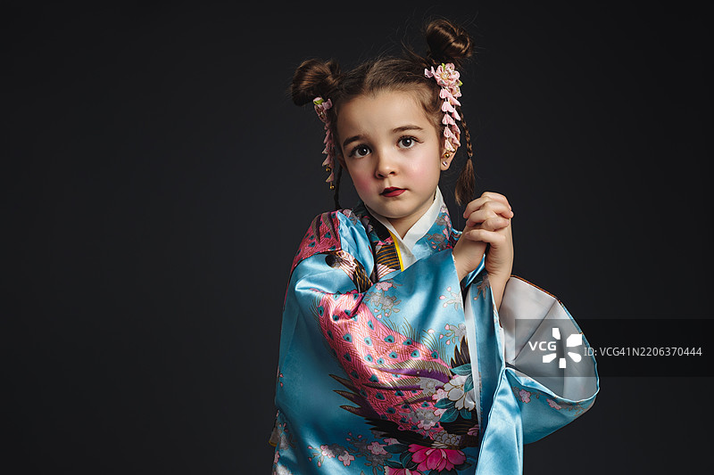 穿着传统日本和服的小女孩在摄影棚摆姿势图片素材