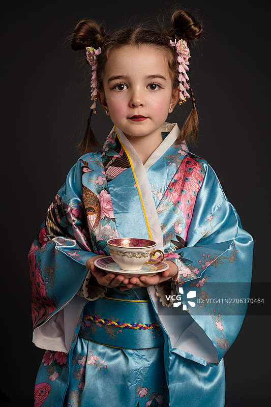 穿着和服的小女孩手捧茶杯和茶托图片素材