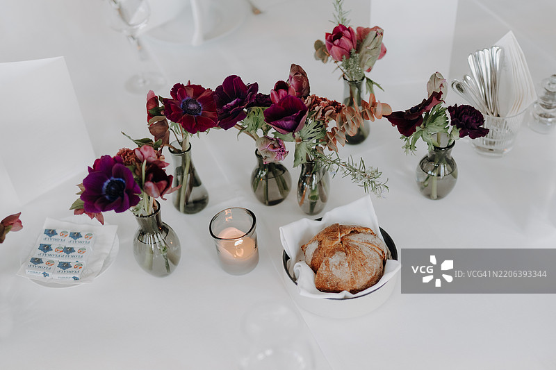 优雅的婚礼接待桌，配有花卉装饰、银莲花和蜡烛图片素材
