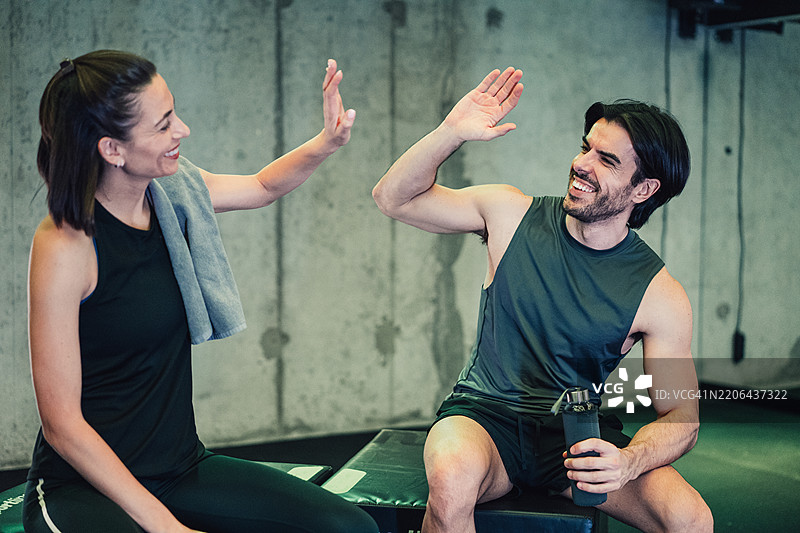 一对情侣在健身房成功锻炼后互相击掌庆祝。图片素材