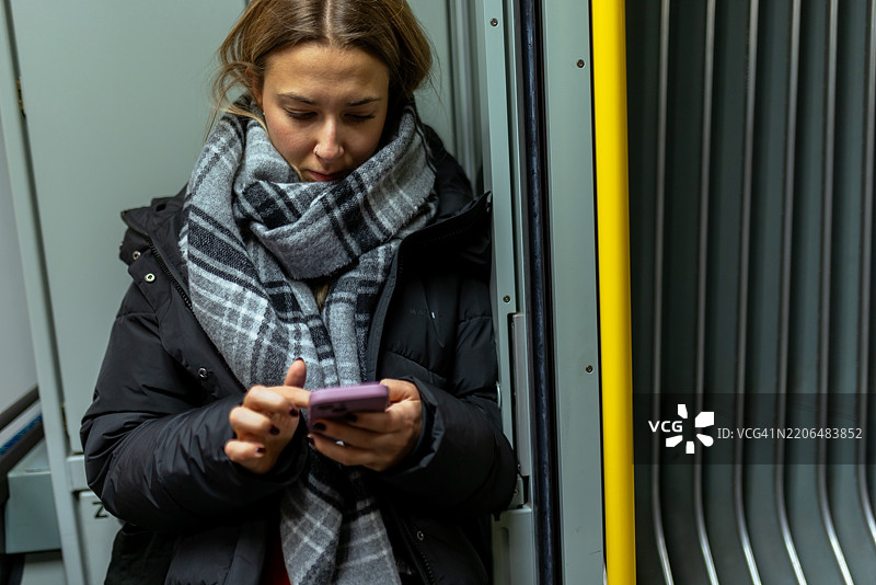 一位女性正在用手机查看地铁列车的到达时间图片素材