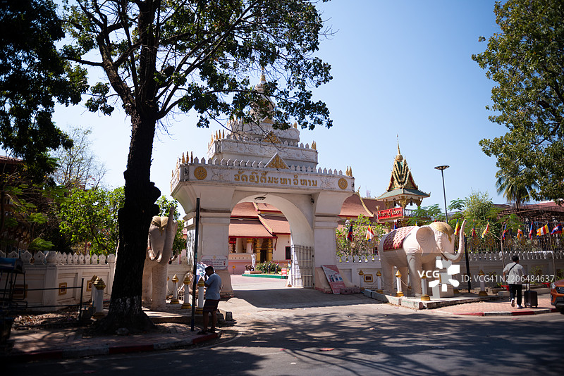 一座华丽的佛教寺庙大门，带有拱门和尖塔，装饰着精美的雕刻和金色点缀，矗立在老挝的万象。图片素材