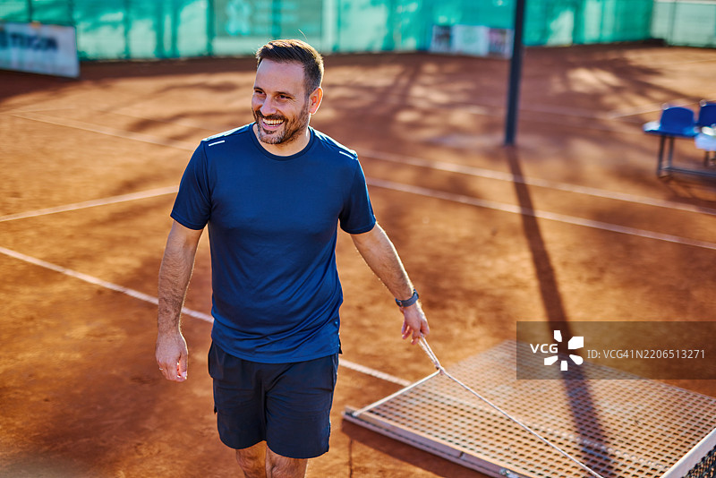 网球教练在比赛后拉动场地上的拖网。图片素材