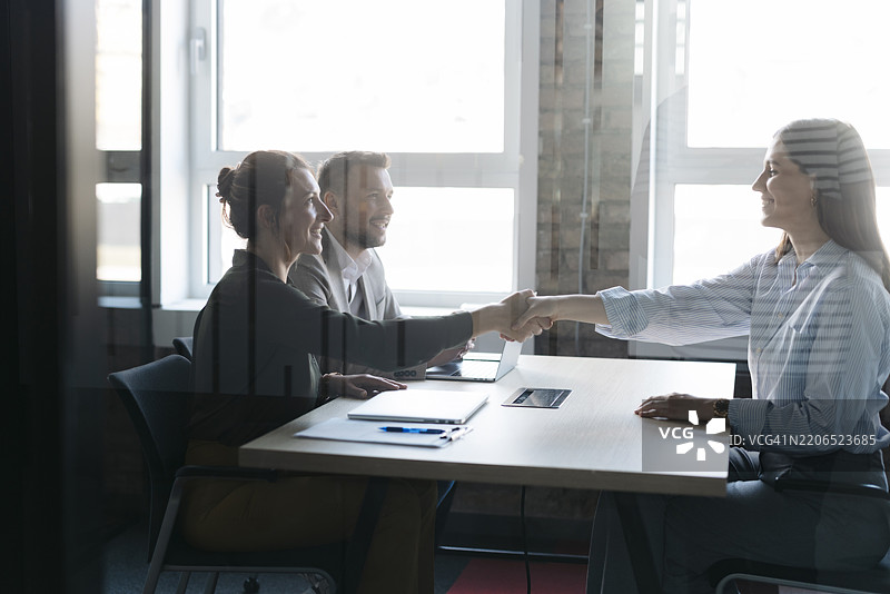 现代办公室中，成功面试后的女商人握手。图片素材