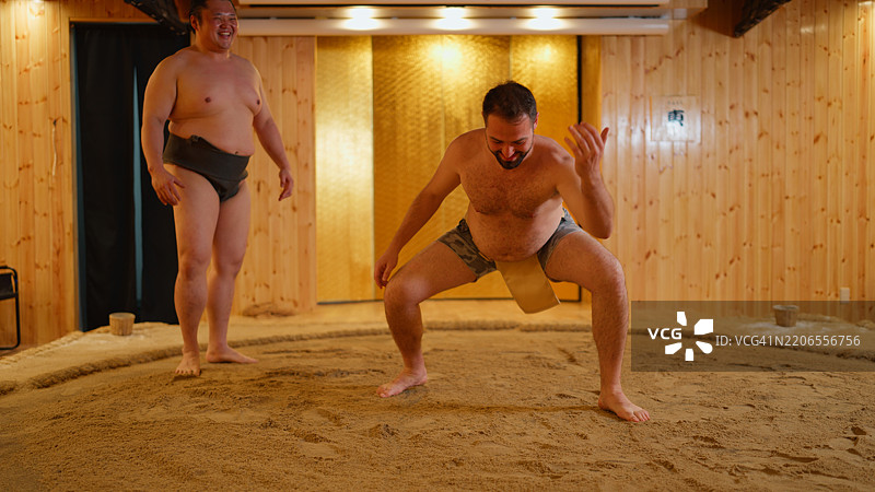 男性游客在日本向前职业相扑选手学习日本传统相扑。图片素材