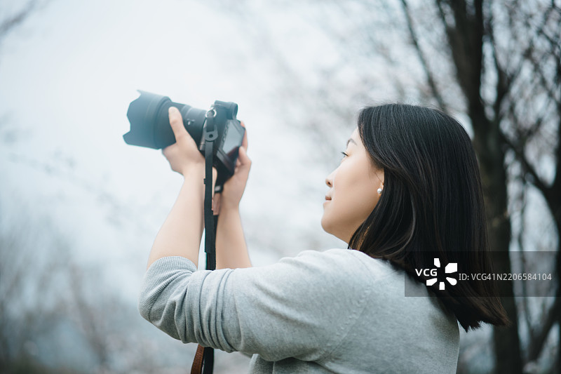 亚洲女性在拍摄樱花图片素材