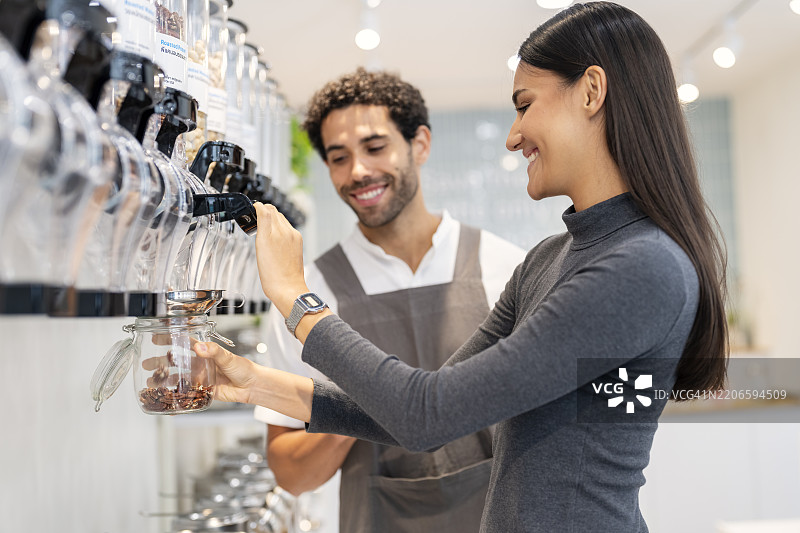 男性店主在补货店里为女性顾客提供建议。图片素材