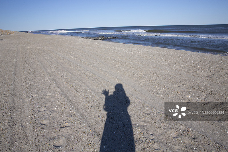 独自旅行，沙滩上的影子自拍，向沙子上的人挥手问好图片素材