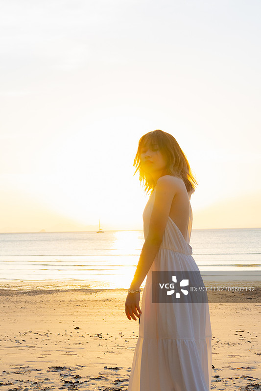 在泰国甲米的莱利海滩，一个阳光明媚的日子里，一位年轻的女性旅行者正在欣赏白沙滩和喀斯特自然岩石形成的壮丽景色。图片素材