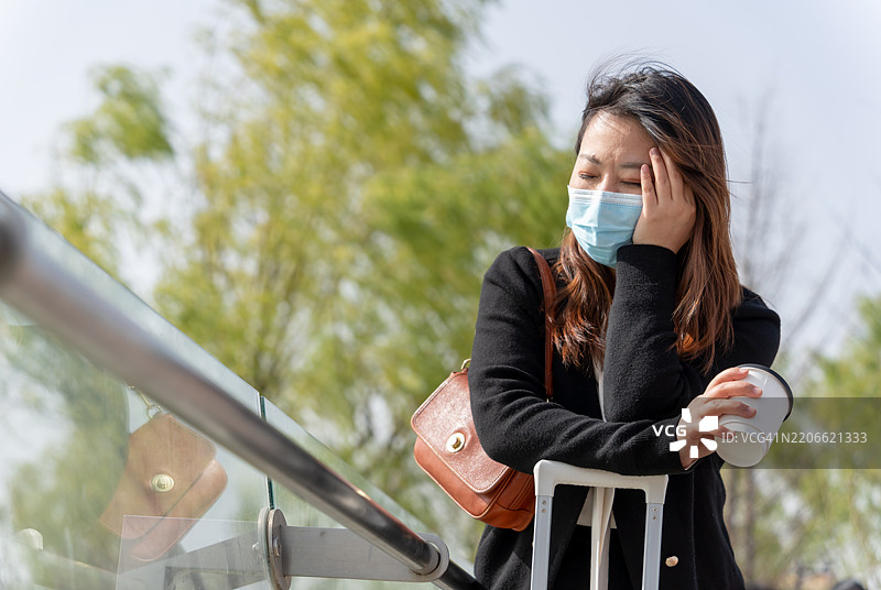 一位亚洲女性在旅行中感到头痛并皱眉。图片素材