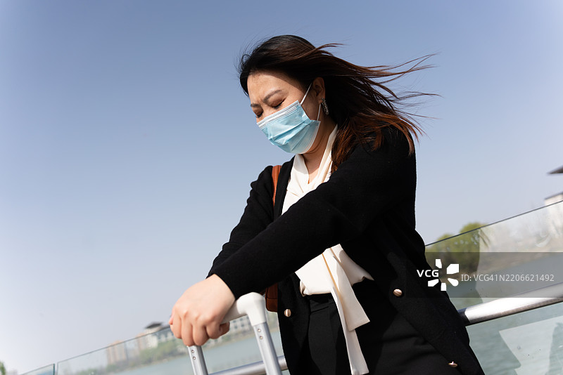 一位亚洲女性在旅行中感冒并头痛图片素材