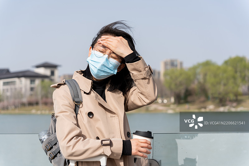 一位亚洲女性在旅行中感到头痛并皱眉。图片素材