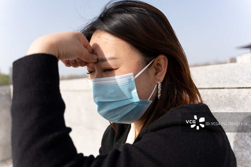 一位亚洲女性在旅行中感到头痛并皱眉。图片素材