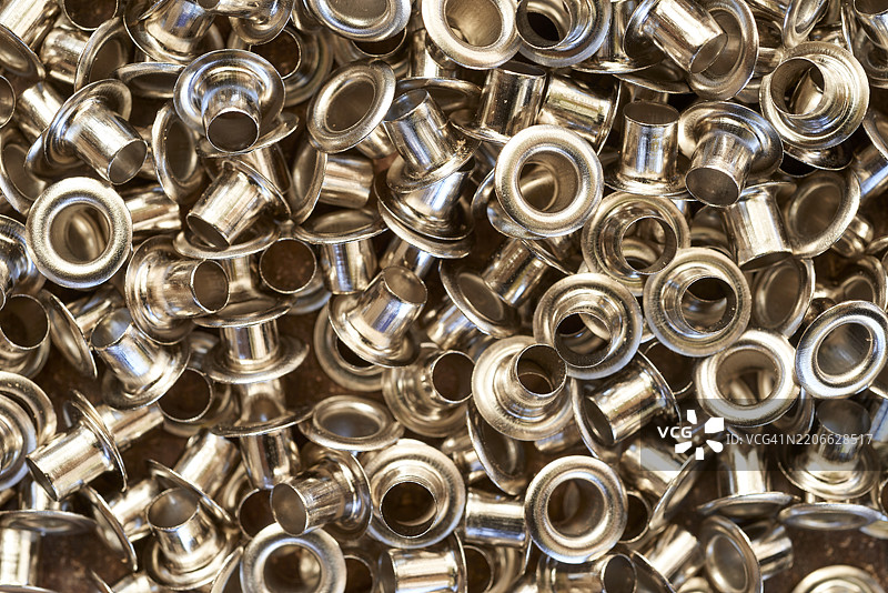 抛光金属眼圈形成复杂的纹理图案,展现出具有反射光泽和几何精度的工业金属表面,适用于制造设计背景。图片素材