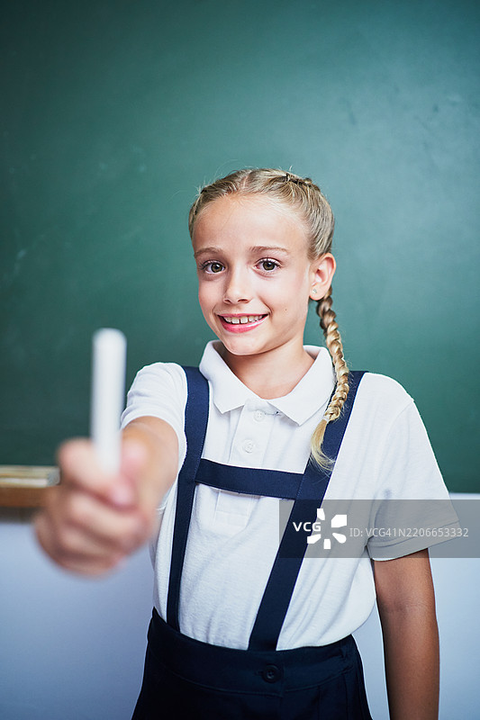 小学学生在黑板前拿着粉笔图片素材