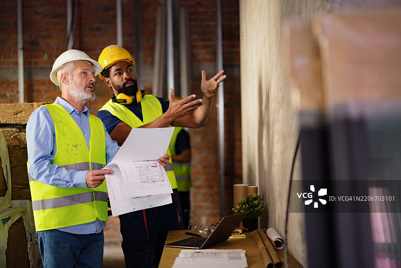 两名建筑工人在工地上讨论蓝图图片素材