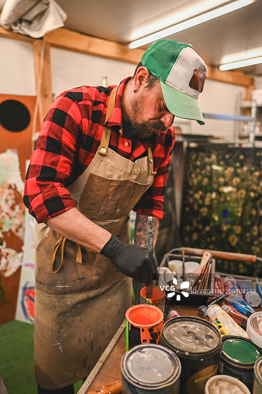 艺术家穿着围裙和手套在艺术工作室调配颜料图片素材