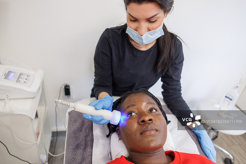 非裔美国女性在专业LED面部护理中放松图片素材